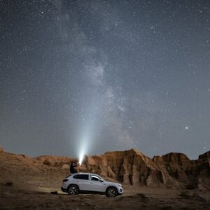 Beach Scenery - A person stands on an SUV under a vast starry ni #3064258