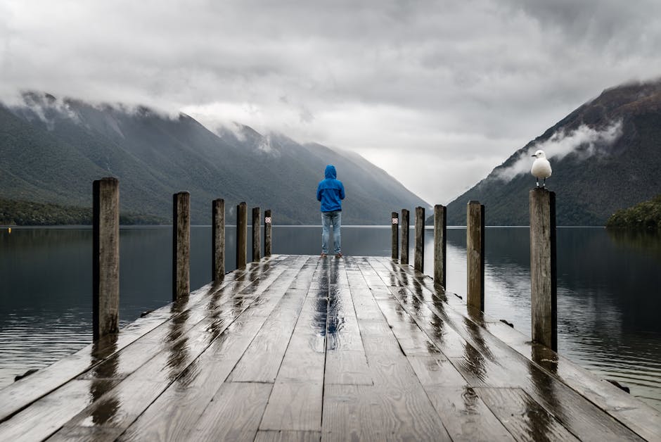 Lake Reflections - Person in blue jacket stands on a rainy dock ove #395196