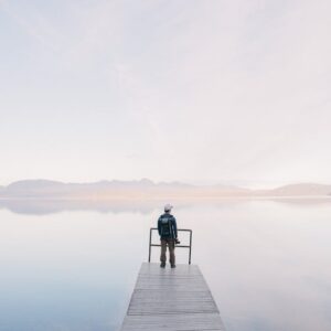 Lake Reflections - A solitary traveler stands on a dock enjoying th #571169