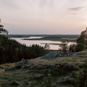Lake Reflections - A couple enjoys a serene walk on a rocky cliff o #6317945